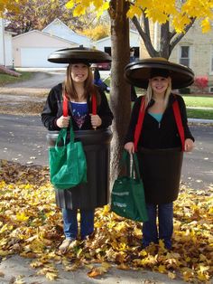 two women standing next to each other in front of a tree with bags on their heads