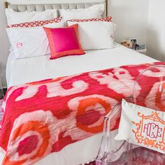 a bed with pink and orange pillows on top of it