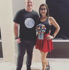 a man and woman standing next to each other in front of a building with balloons