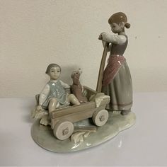 a figurine of a woman pushing a child in a wagon