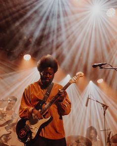 a man standing in front of a microphone while holding a guitar