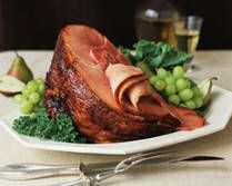 a plate with ham, grapes and other food items on the table next to wine glasses