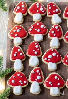 cookies decorated with red and white mushrooms on a wooden board