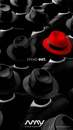 a red hat sitting in the middle of a crowd of black hats that say stand out