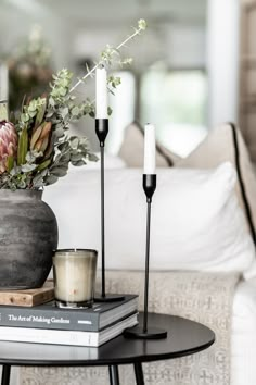 a table with candles and flowers on top of it next to a couch in a living room