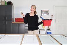 a woman holding a brush in her hand while standing next to some cabinets and drawers