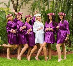 a group of women in purple robes standing next to each other holding wine glasses and flowers