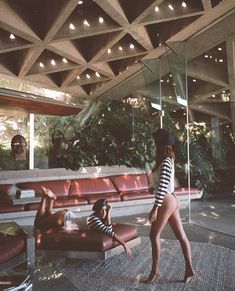 two women in striped shirts are walking through an airport lobby with red leather couches