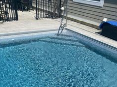 an empty swimming pool in front of a house with a blue towel on the edge