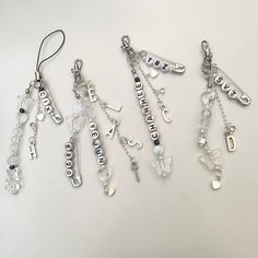 several charms are hanging on a white surface with the word love spelled in cursive letters