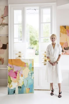 an older woman standing in front of paintings