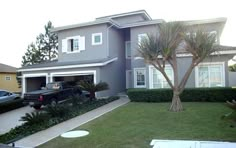 a car is parked in front of a house with palm trees on the side walk