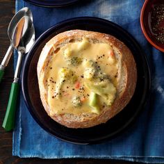 a bowl of soup with broccoli and cheese in it on a blue place mat