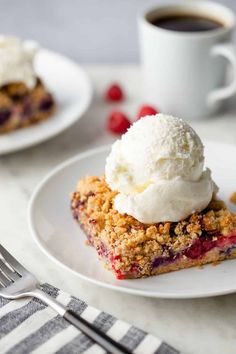 a slice of berry crumble cake on a white plate with ice cream and raspberries