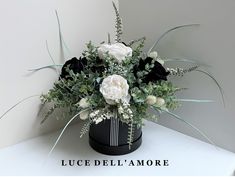 a black and white flower arrangement in a vase on a table with the words luce dell'amore above it