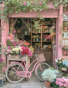 a pink bicycle parked in front of a flower shop