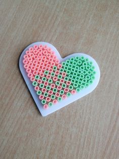 a heart shaped beaded object sitting on top of a wooden table