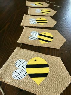 burlap tags with bees and polka dots hanging on a wooden table in the shape of hearts