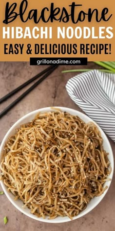 a white bowl filled with noodles next to chopsticks on top of a table