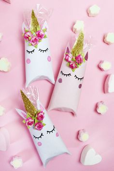 two unicorn candy bags with pink roses and gold glitter on them, sitting next to each other