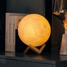 a yellow moon lamp sitting on top of a table next to a bookshelf