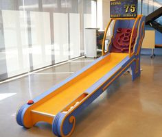 an orange and blue children's slide in the middle of a room with windows