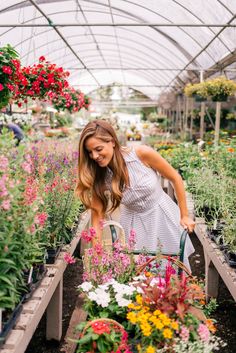 a woman tending to flowers in a greenhouse