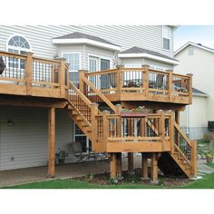 a wooden deck with railings and planters on the side of it in front of a house