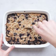 someone is placing toppings on top of a blueberry baked oatmeal