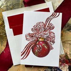 two red and white christmas cards on top of each other next to some gold foil