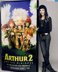 a woman standing next to a poster for the movie arthrir 2 and other movies