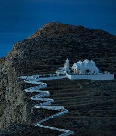 a white church on the side of a hill at night with stairs leading up to it