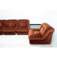 a brown couch and chair sitting next to each other on a white floor with a mirror in the corner