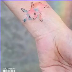 a small tattoo on the wrist of a person with a pink and blue ink design