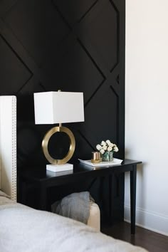 a black and white bedroom with a gold lamp on the end table next to a bed