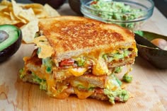 a grilled cheese sandwich with guacamole and chips on a cutting board