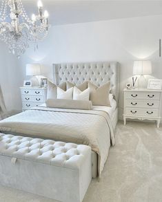 a bedroom with white furniture and chandelier