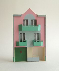 a doll house with green and pink balconies