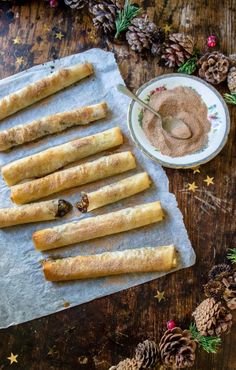 breadsticks are lined up on a piece of parchment paper next to a bowl of nutella