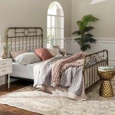 a bedroom with a bed, dresser and rug on the hardwood floor in front of an arched window