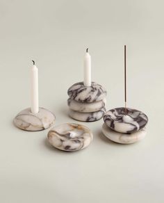 marble candlesticks and plates with one candle in the middle on a white background