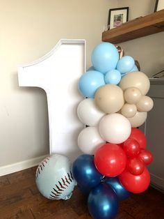 a number one balloon column with baseballs and balloons on the floor next to it