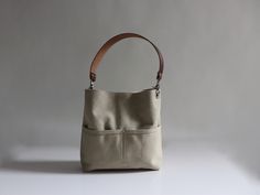 Our soft, sun-washed canvas bucket bag will quickly become your favorite everyday bag. A mid-sized bag in a neutral Sand color with plenty of pockets and the flexibility to choose a shoulder strap, a crossbody strap or both. Versatile, durable and a breeze to carry. To see additional colors and sizes click here: https://www.etsy.com/shop/IndependentReign DETAILS: -Approximately 10.5in H x 11in W x 2.5in D -Durable canvas exterior with a subtle faded finish -2 exterior front pockets -Magnetic sna Everyday Canvas Bucket Hobo Bag, Modern Canvas Crossbody Hobo Bag, Modern Crossbody Canvas Hobo Bag, Cotton Bucket Bag With Leather Handles For Everyday Use, Khaki Canvas Hobo Bag Tote, Canvas Bucket Bag With Leather Handles For Everyday Use, Everyday Canvas Bucket Bag With Removable Pouch, Cream Canvas Hobo Bag With Adjustable Strap, Cream Canvas Hobo Bag