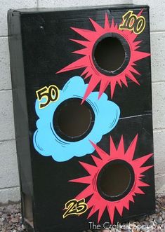 a black box with red, blue and yellow designs on the side sitting in front of a white brick wall