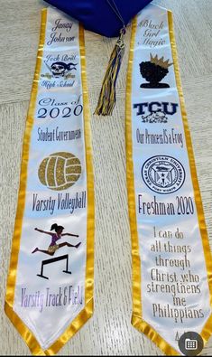 two ribbons with different designs on them sitting on a table next to a blue graduation cap