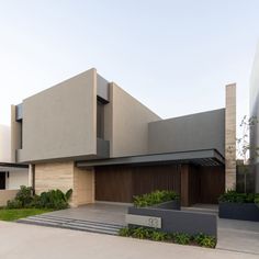 a modern house is shown in the middle of an empty lot with grass and bushes