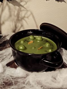 a black bowl filled with green liquid on top of a pile of white fluffy material