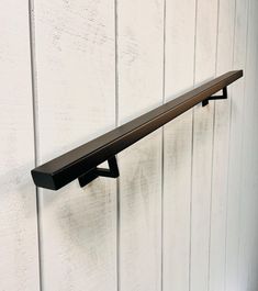 a metal shelf mounted to the side of a white painted wall with wood planks