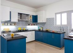 a kitchen with blue and white cabinets, black counter tops, and yellow accessories on the counters