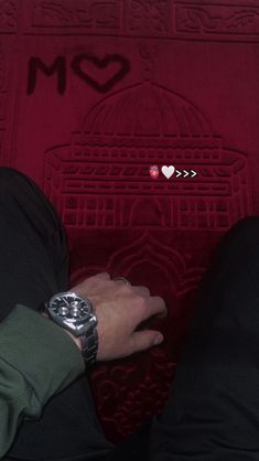 two people holding hands in front of a red wall with hearts drawn on the floor